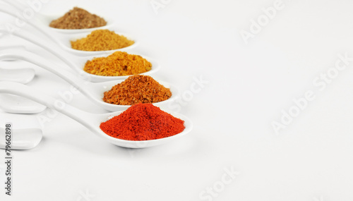 Different kinds of spices in ceramics spoons isolated on white