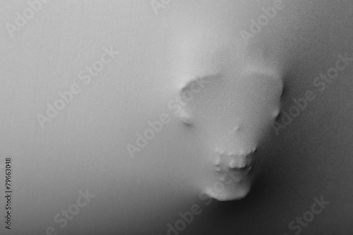 Skull pressing through fabric as horror background