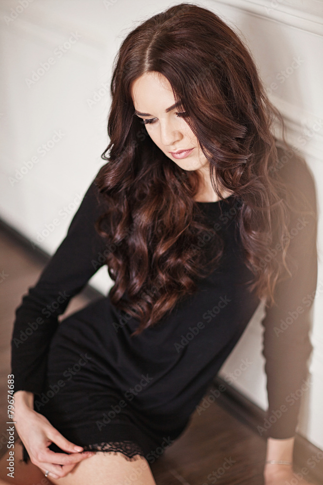 Young brunette lady in black lacy dress posing in white room. Young brunette lady in black lacy dress posing in white room.