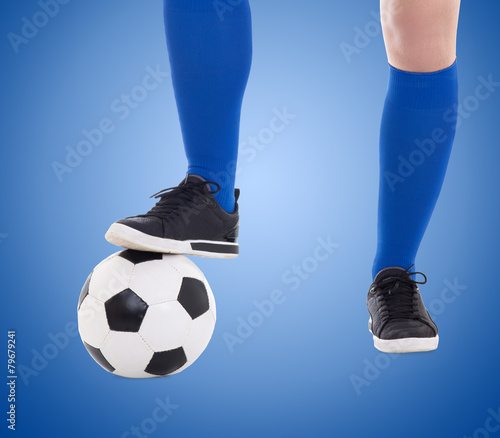 legs of soccer player and ball close-up over blue