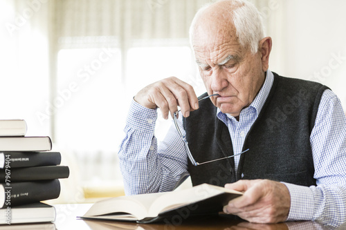 Senior man reading book relaxed at home