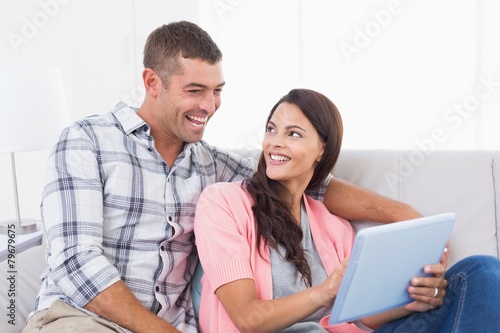 Couple with digital tablet sitting on sofa