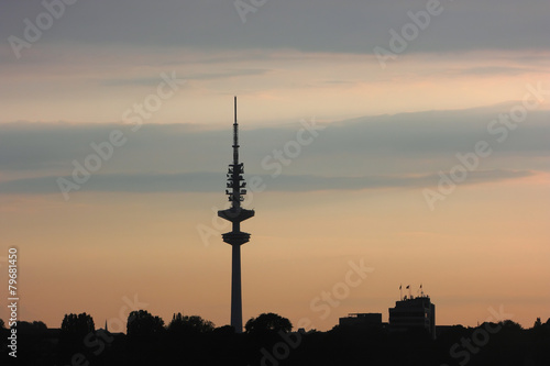 Hamburg TV tower. The contour of TV tower of Hamburg against the evening sky with a stripes of clouds and dark outline of the city.