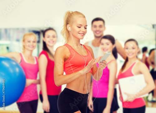 smiling sporty woman with smartphone and earphones