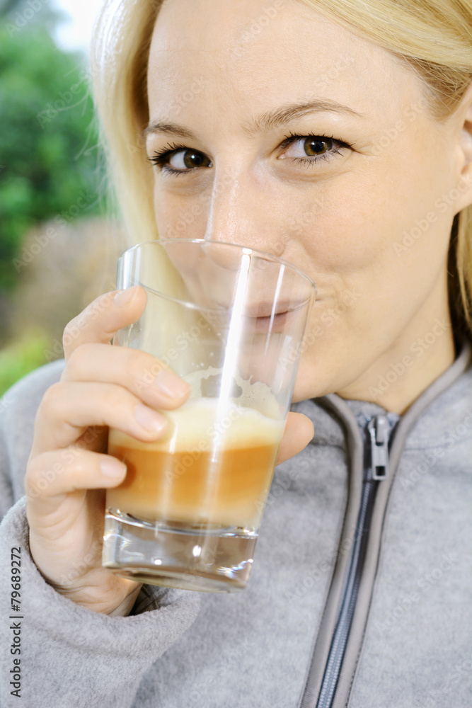 Frau in Fleecejacke trinkt Milch-Kaffee Frau in Fleecejacke trinkt Milch-Kaffee