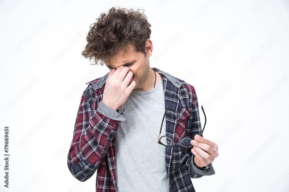 Handsome young man rubs his eyes and holding glasses Handsome young man rubs his eyes and holding glasses