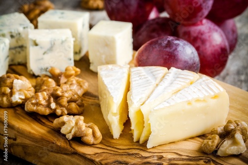 camembert cheese close-up with nuts and grape on a wooden board