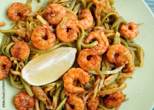 shrimps and zucchini cutting as noodles in green plate, close-up