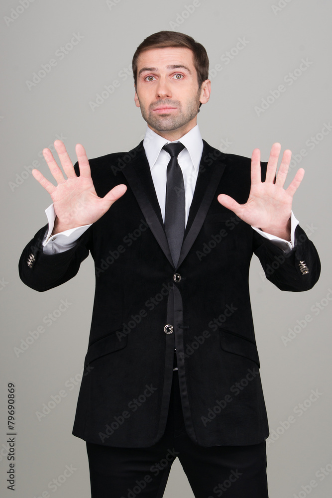 Young business man in black suit making calm down gesture. Studi Stock  Photo