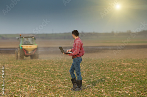 Peasant with laptop on farmland