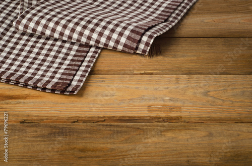 Brown checkered Tablecloth textile on a wooden background