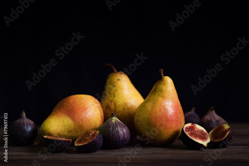 Still life with yellow pears and figs on a wooden table