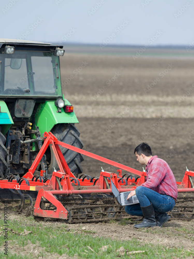 Fototapeta premium Farmer with laptop and tractor