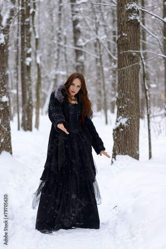 Woman in black dress in winter forest