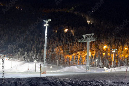 Fotografie Skiing at night - a snowpark and ski slope illuminated  at night in ski resort L