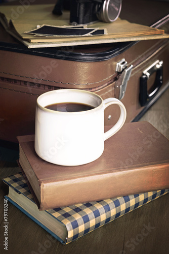 Vintage suitcase with books and camera on wooden background