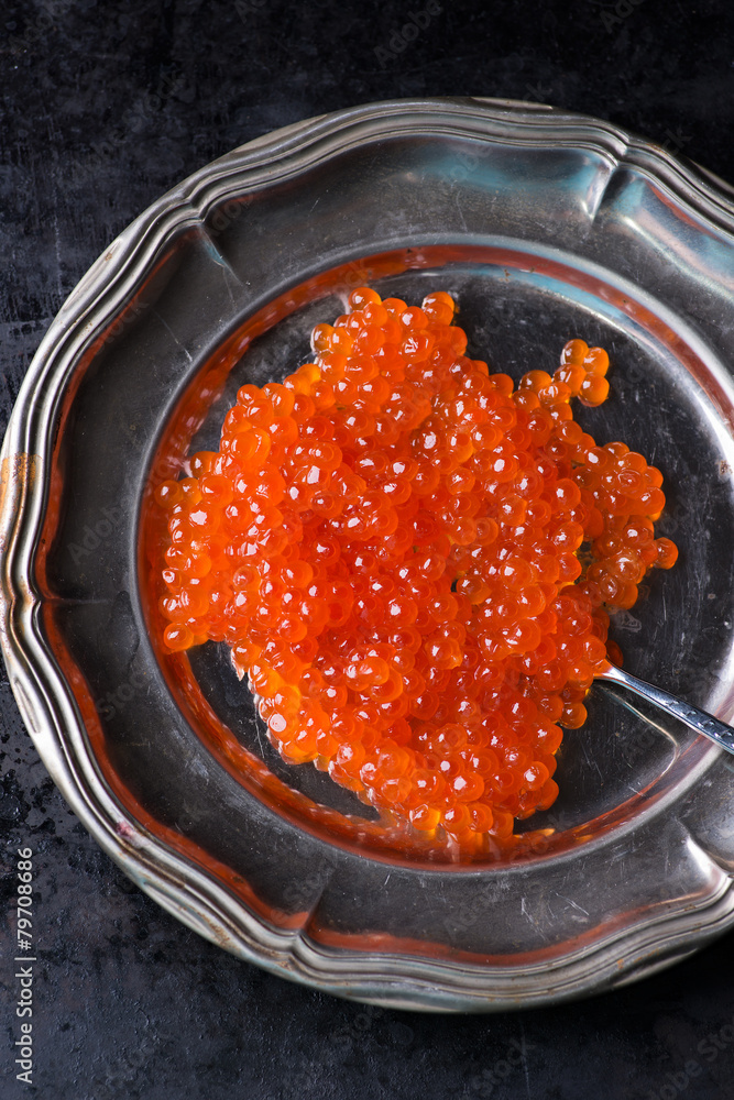 Salmon caviar on metal plate over dark background Salmon caviar on metal plate over dark background