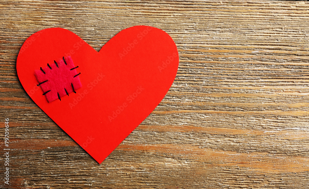 Obraz premium Patch on broken heart on wooden background