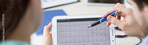 Modern cardiologists analyzing electrocardiogram