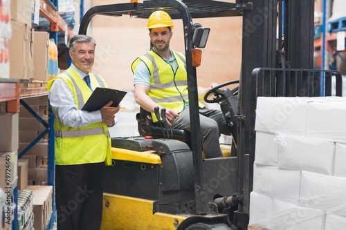 Driver operating forklift machine next to his manager