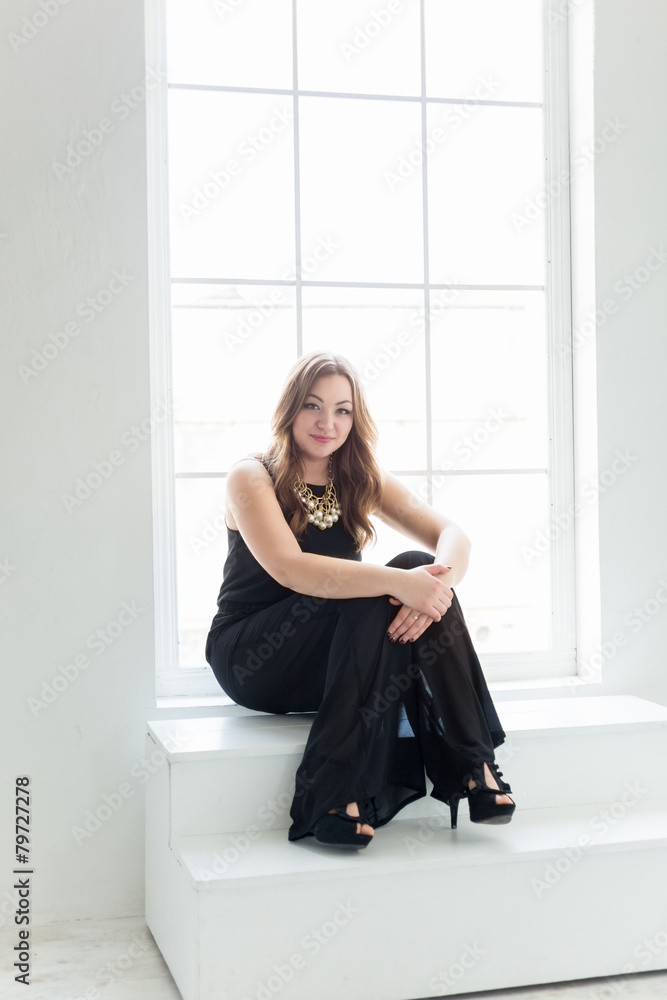 young woman in long black dress sitting on stairs at big window young woman in long black dress sitting on stairs at big window