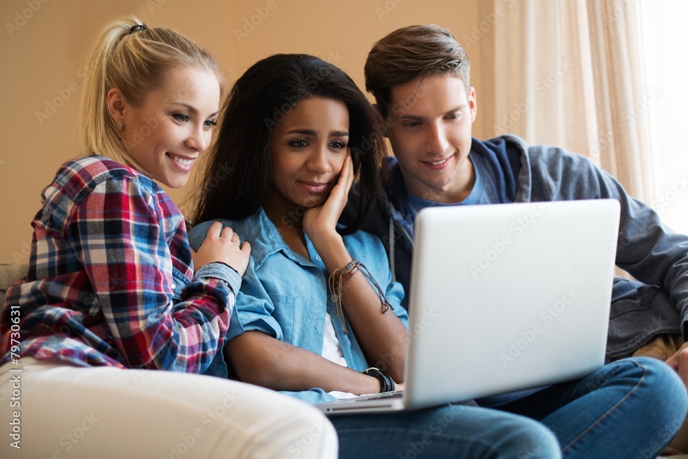 Three young students with laptop in home interior Three young students with laptop in home interior