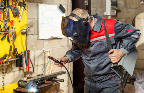 Welder worker in protective mask welding metal