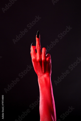 Red devil hand with black nails showing middle finger