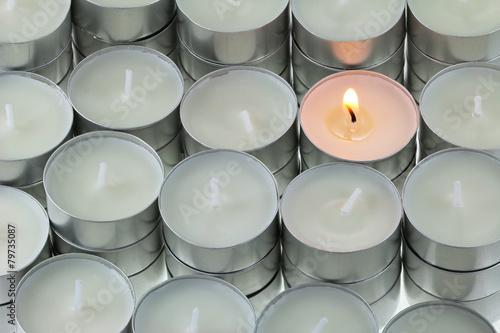 Closeup of Tea lights candle with one being lit photo