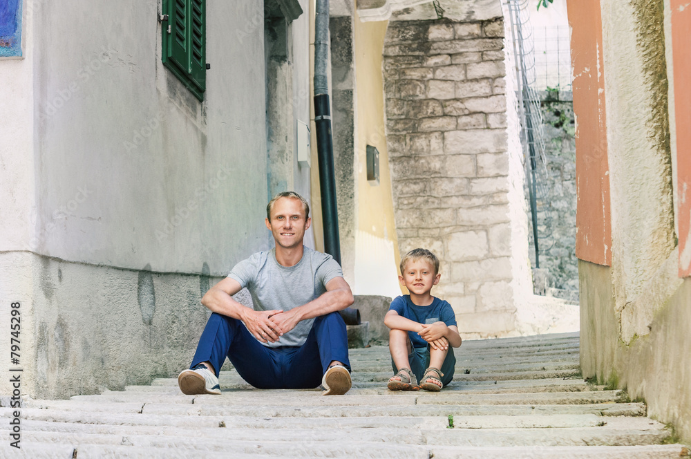Father and little son siting on the Old Croatian town street