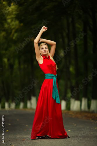 Portrait of dancing woman at forest in red dress