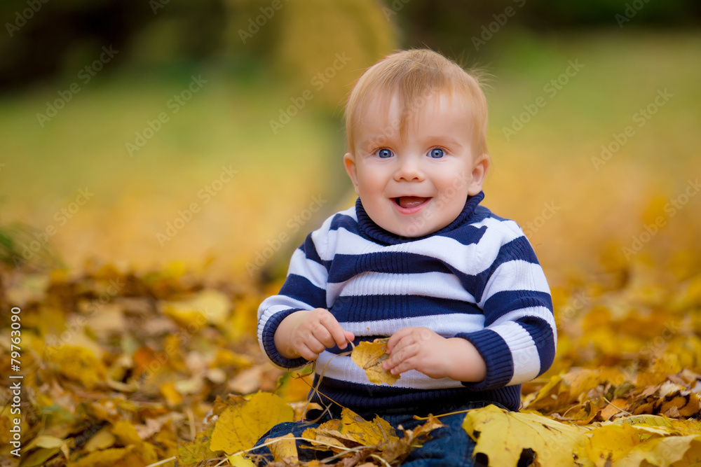 Little boy playing in yellow foliage. Autumn in the city park Little boy playing in yellow foliage. Autumn in the city park