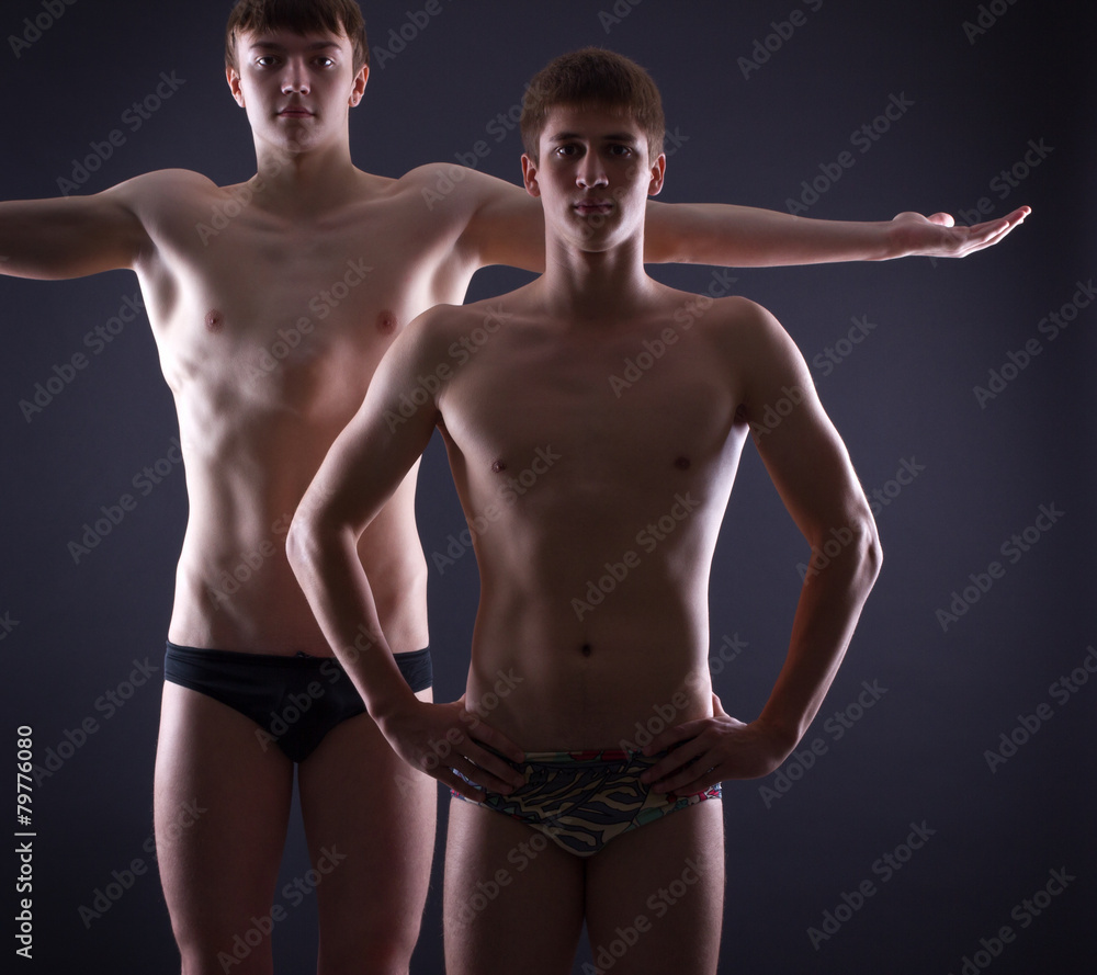Two muscular men posing on a dark background.