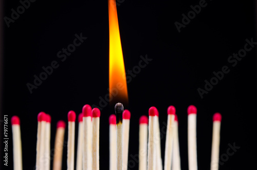 many red matches on black background (one match burns)