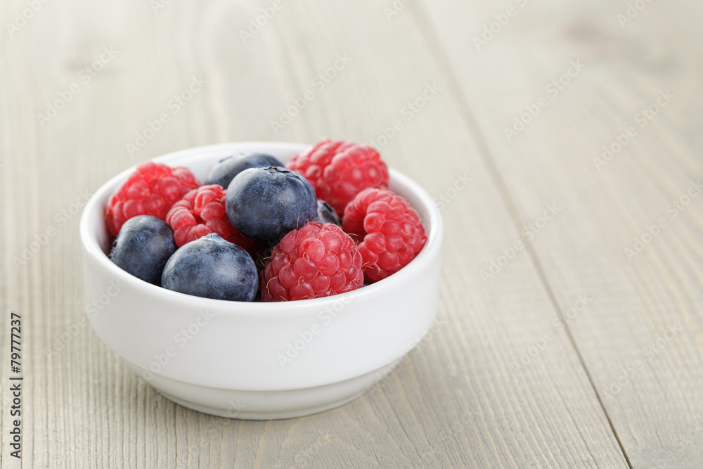 blueberries and raspberries in bowl on wooden table blueberries and raspberries in bowl on wooden table
