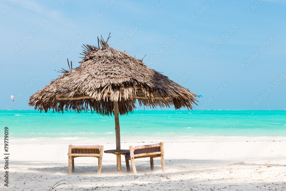 Two deck chairs and umbrella on tropical beach.