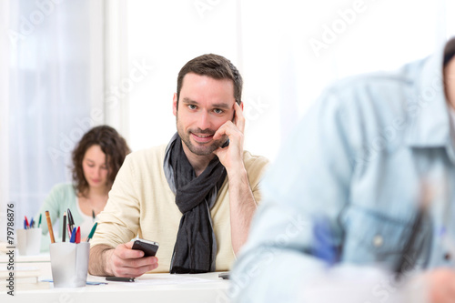 Young attractive student using his mobile during classes