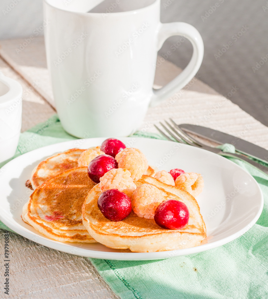 pancakes with cherry and raspberry on a round plate