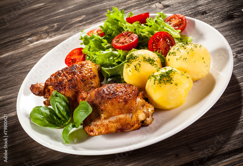 Barbecued chicken legs with boiled potatoes and vegetables