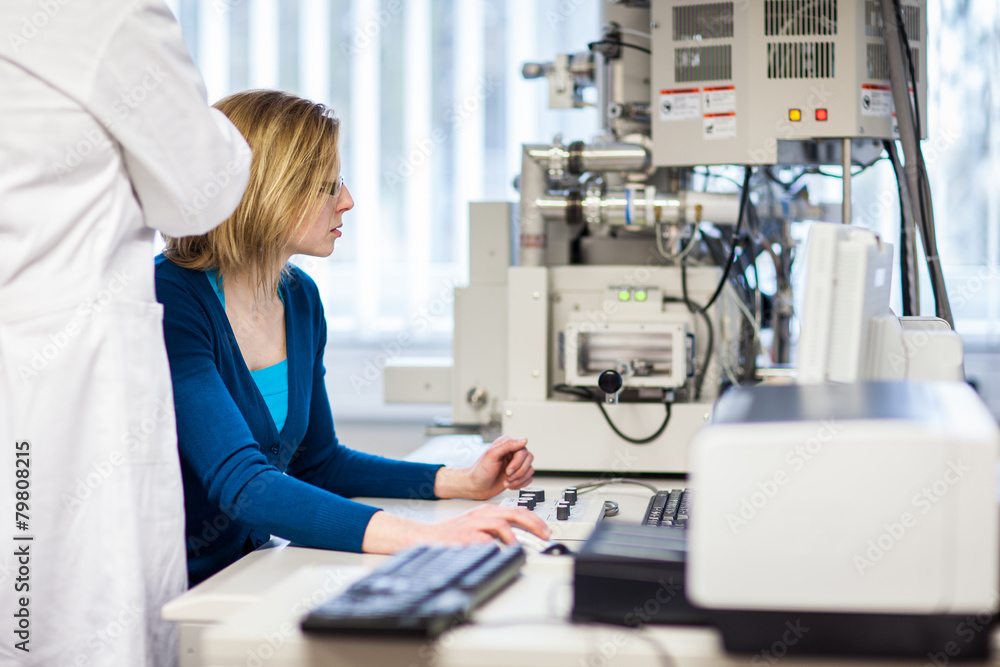 Pretty, female researcher using a microscope in a lab, doing res Pretty, female researcher using a microscope in a lab, doing res