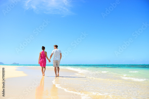 Beach couple holding hands walking on honeymoon