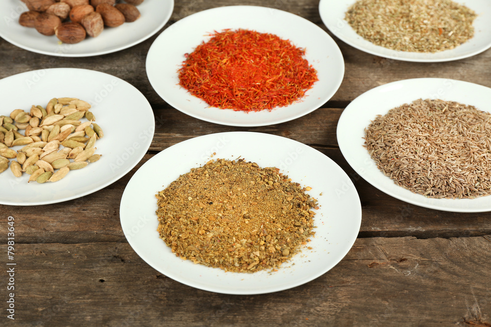 Different spices on plates, on old wooden table Different spices on plates, on old wooden table