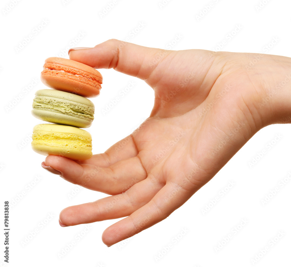 Tasty colorful macaroons in female hand isolated on white Tasty colorful macaroons in female hand isolated on white