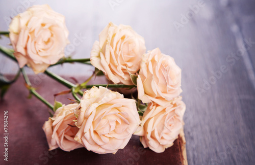 Roses with vintage book on wooden table background