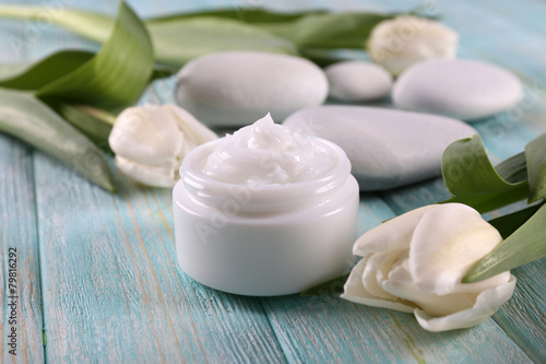 Fototapeta Naklejka Na Ścianę i Meble -  Cosmetic cream with flowers and spa stones on wooden background