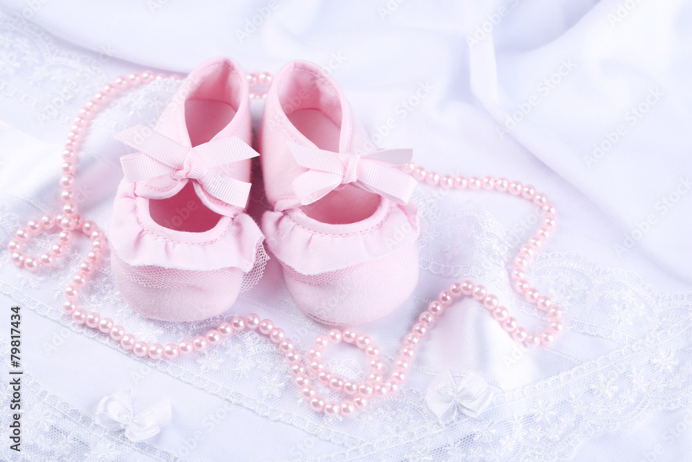 Pink baby boots on cloth close-up Pink baby boots on cloth close-up