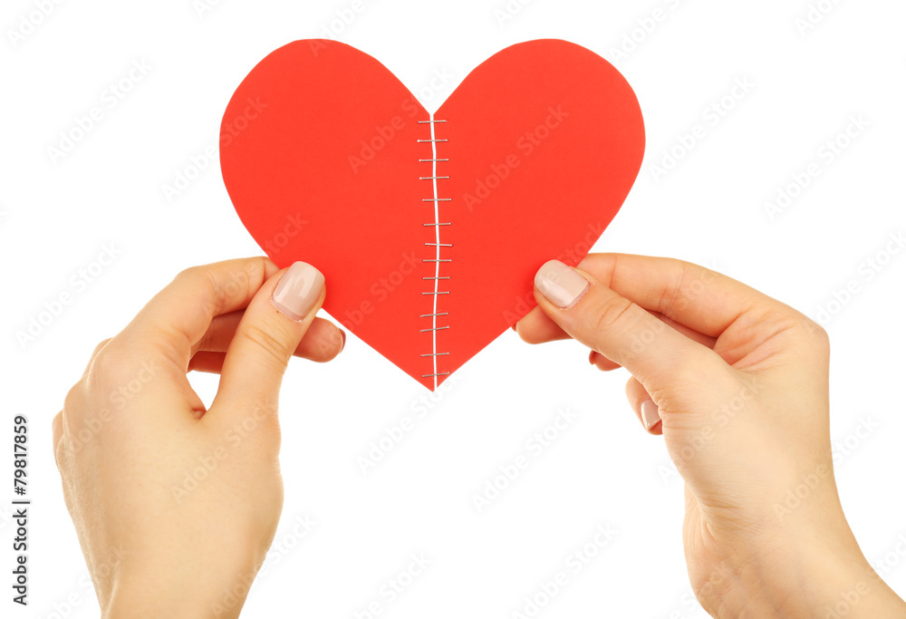 Female hands holding broken heart stitched with staples Female hands holding broken heart stitched with staples
