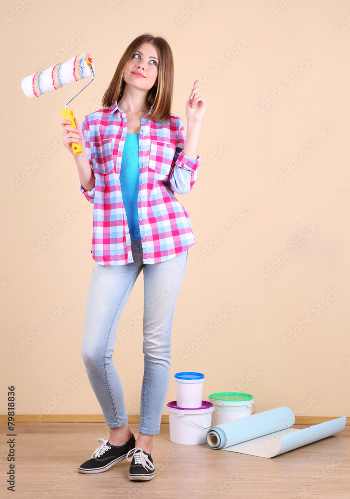 Beautiful girl with roller and paints in room Beautiful girl with roller and paints in room