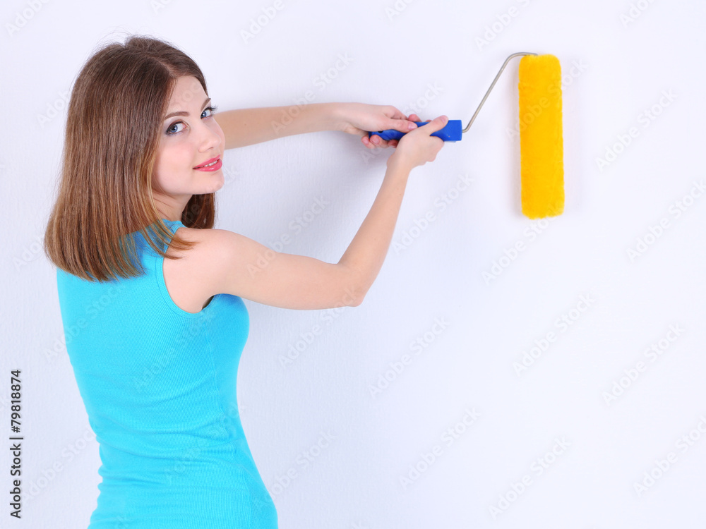 Beautiful girl paints wall in room Beautiful girl paints wall in room