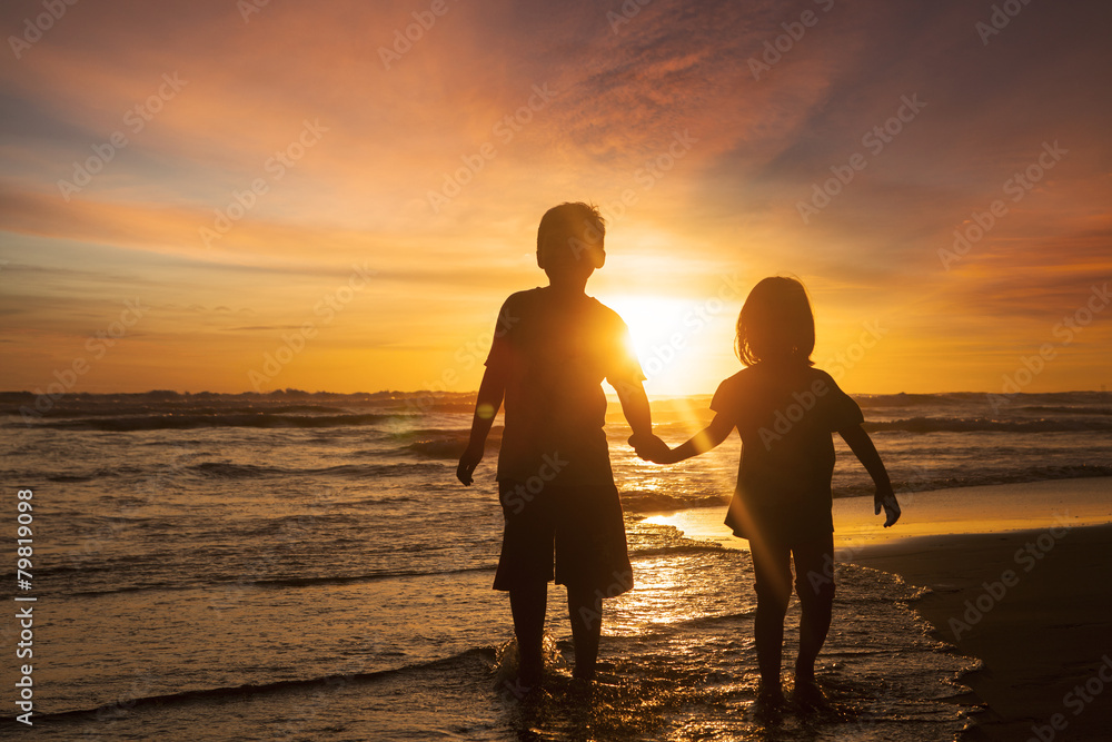 Two children holding hands at beach